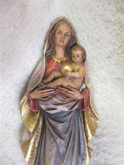 detail draperie a červené stuhy v rukou Madony